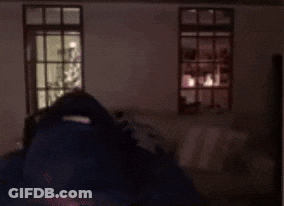 A Man With A Beard And Headphones Is Standing In Front Of A Window . GIF