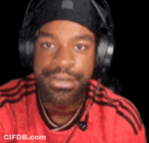 A Man With A Beard And Headphones Is Wearing A Red Shirt And A Black Hat . GIF