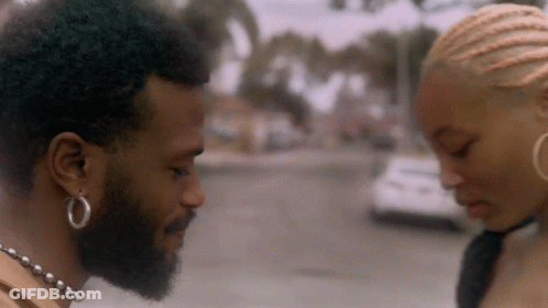 A Man With A Beard And Hoop Earrings Is Looking At A Woman GIF