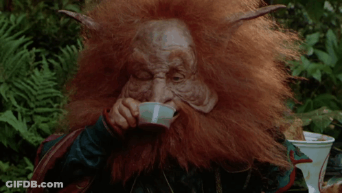 A Man With A Beard And Horns Is Holding A Bottle In Front Of His Face GIF