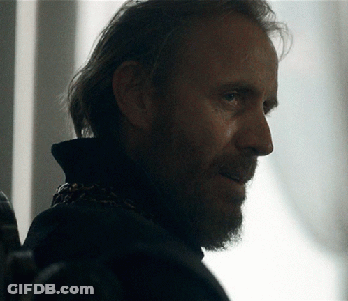 A Man With A Beard And Long Hair Is Looking At Something GIF