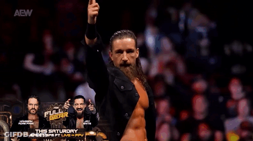 A Man With A Beard And Long Hair Is Standing In Front Of A Crowd With His Arms In The Air . GIF