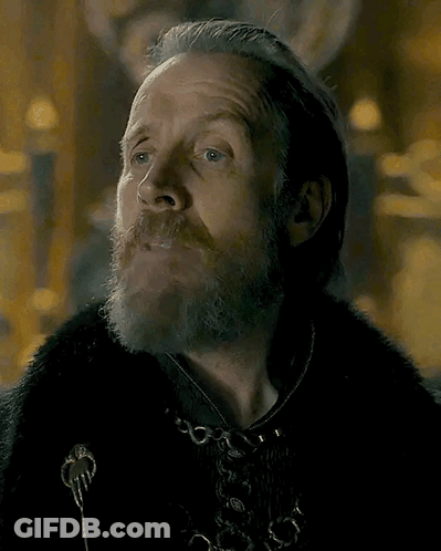 A Man With A Beard And Long Hair Is Wearing A Fur Coat . GIF