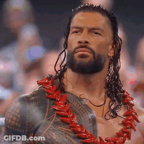 A Man With A Beard And Long Hair Is Wearing A Red Necklace . GIF