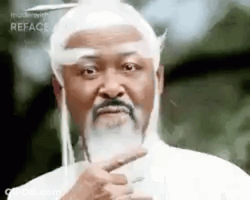 A Man With A Beard And Long White Hair Is Pointing At Something . GIF