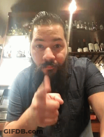 A Man With A Beard And Mustache Holds His Finger To His Mouth GIF