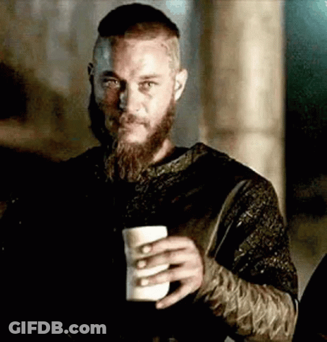A Man With A Beard And Mustache Is Holding A Cup Of Coffee . GIF