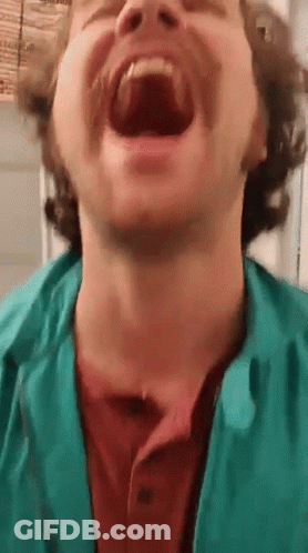 A Man With A Beard And Mustache Is Laughing With His Mouth Open . GIF