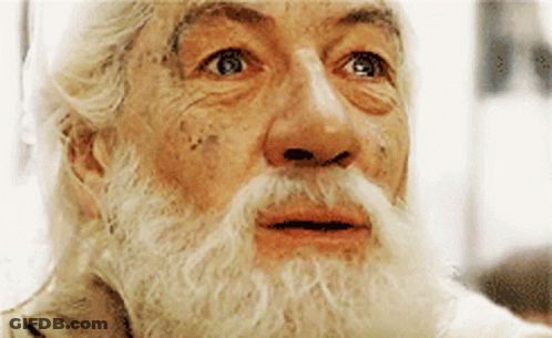 A Man With A Beard And Mustache Is Looking At Something GIF