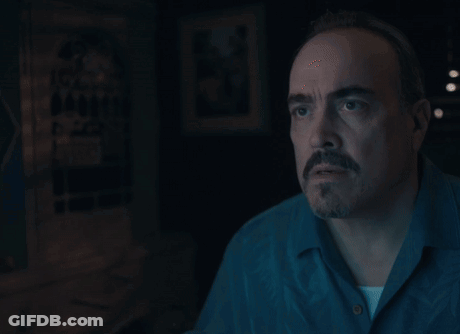 A Man With A Beard And Mustache Is Looking At Something In The Dark GIF