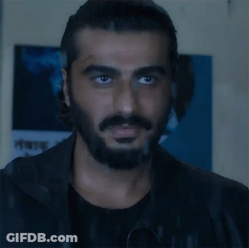 A Man With A Beard And Mustache Is Looking At The Camera In Front Of A Sign That Says ' A ' On It GIF