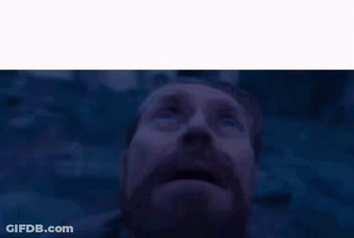 A Man With A Beard And Mustache Is Looking Up At The Sky In A Dark Room . GIF