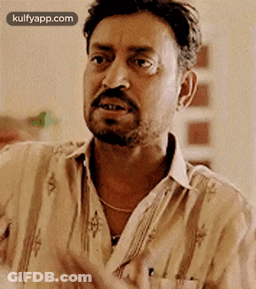 A Man With A Beard And Mustache Is Making A Funny Face While Wearing A Striped Shirt . GIF