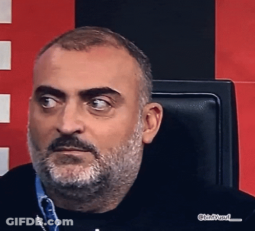 A Man With A Beard And Mustache Is Sitting In A Chair With Bin / Yusuf Written On The Bottom Right GIF