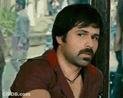 A Man With A Beard And Mustache Is Sitting In Front Of A Window . GIF