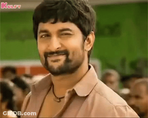 A Man With A Beard And Mustache Is Smiling And Looking At The Camera . GIF