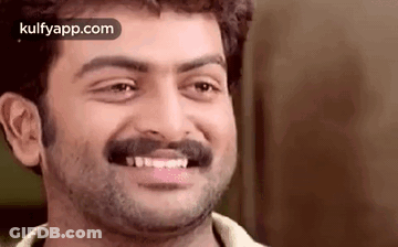 A Man With A Beard And Mustache Is Smiling And Looking At The Camera . GIF