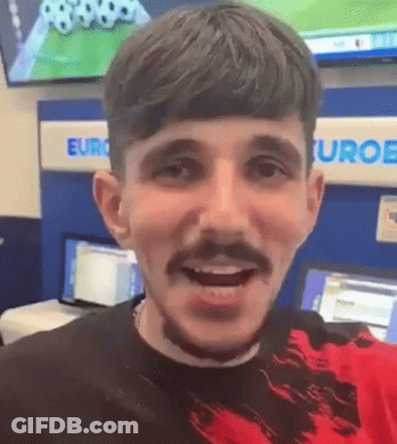 A Man With A Beard And Mustache Is Smiling And Looking At The Camera . GIF