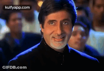 A Man With A Beard And Mustache Is Smiling In Front Of A Crowd . GIF