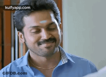 A Man With A Beard And Mustache Is Smiling With His Eyes Closed And Wearing A Blue Shirt . GIF