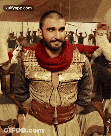 A Man With A Beard And Mustache Is Standing In Front Of A Crowd Of People . GIF