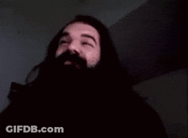 A Man With A Beard And Mustache Is Waving His Hand In The Dark . GIF