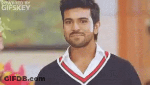 A Man With A Beard And Mustache Is Wearing A Black And Red Sweater And A White Shirt . GIF