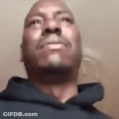 A Man With A Beard And Mustache Is Wearing A Blue Hoodie And Looking Up At The Camera . GIF