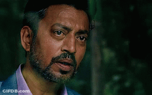 A Man With A Beard And Mustache Is Wearing A Blue Suit And A Purple Shirt . GIF