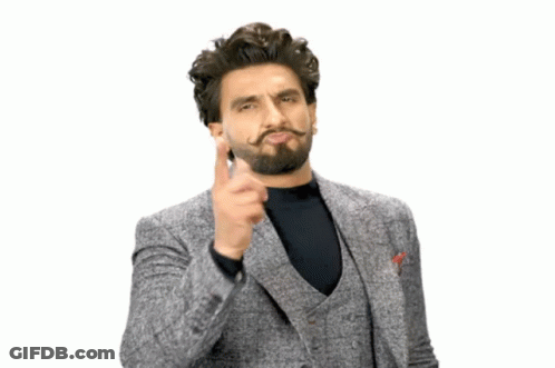 A Man With A Beard And Mustache Is Wearing A Grey Suit And Black Shirt GIF