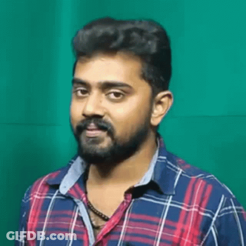 A Man With A Beard And Mustache Is Wearing A Plaid Shirt And Necklace . GIF