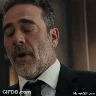 A Man With A Beard And Mustache Is Wearing A Suit And Tie And Yawning . GIF