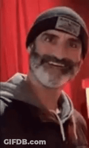 A Man With A Beard And Mustache Wearing A Beanie And A Hoodie . GIF