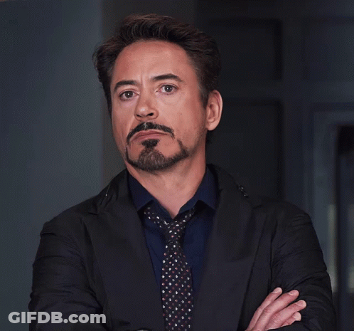 A Man With A Beard And Mustache Wearing A Black Jacket And Tie GIF