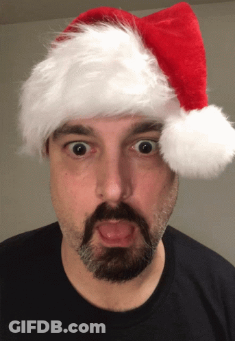 A Man With A Beard And Mustache Wearing A Santa Hat GIF