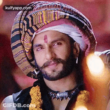 A Man With A Beard And Mustache Wearing A Turban And A Necklace . GIF