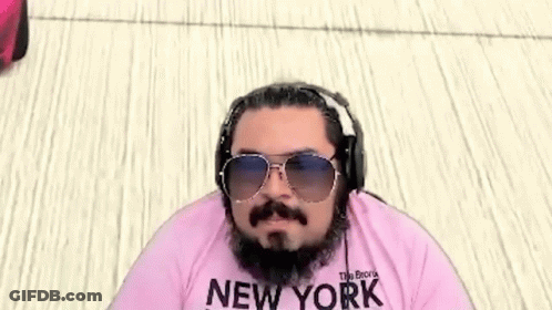 A Man With A Beard And Mustache Wearing Sunglasses And Headphones Is Wearing A Pink Shirt That Says New York . GIF