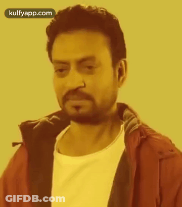 A Man With A Beard And Nose Ring Is Wearing A Red Jacket And White Shirt . GIF