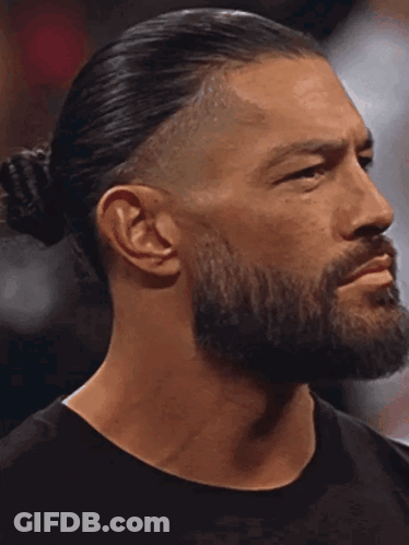 A Man With A Beard And Ponytail Is Looking At The Camera With His Eyes Closed GIF