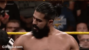 A Man With A Beard And Ponytail Is Standing In A Wrestling Ring . GIF