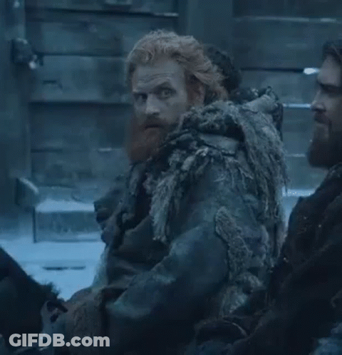 A Man With A Beard And Red Hair Is Sitting Next To Another Man In A Snowy Room . GIF