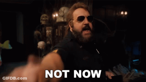 A Man With A Beard And Sunglasses Is Pointing At The Camera With The Words `` Not Now '' Written Next To Him . GIF
