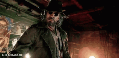 A Man With A Beard And Sunglasses Is Wearing A Hat And A Jacket . GIF
