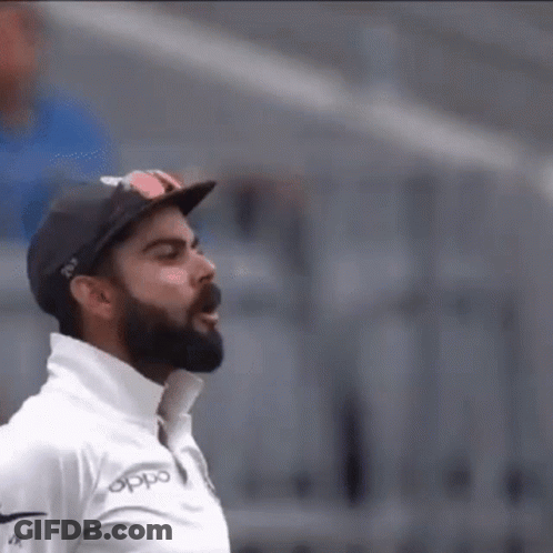 A Man With A Beard And Sunglasses Is Wearing A Hat And A White Shirt . GIF