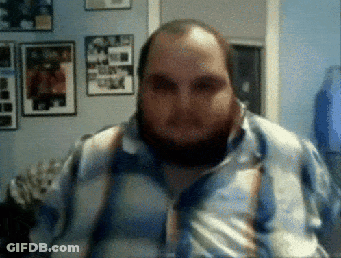 A Man With A Beard And Suspenders Is Looking At The Camera GIF