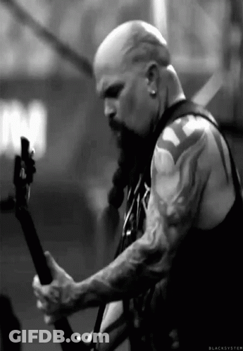 A Man With A Beard And Tattoos Is Playing A Guitar On Stage . GIF