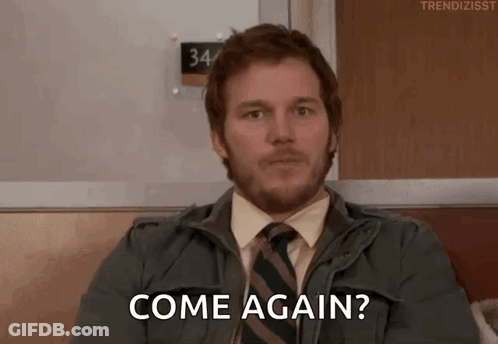 A Man With A Beard And Tie Is Sitting On A Couch And Says Come Again . GIF
