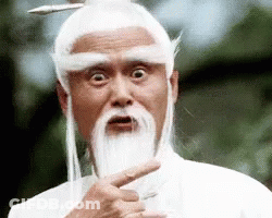 A Man With A Beard And White Hair Is Pointing At The Camera . GIF