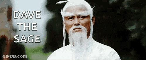 A Man With A Beard And White Hair Is Wearing A White Robe . GIF
