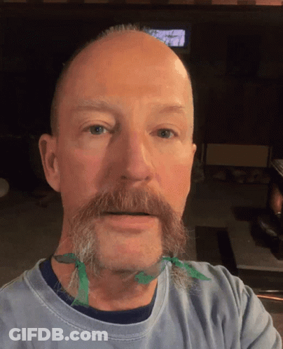 A Man With A Beard Has A Green Ribbon Tied Around His Neck GIF